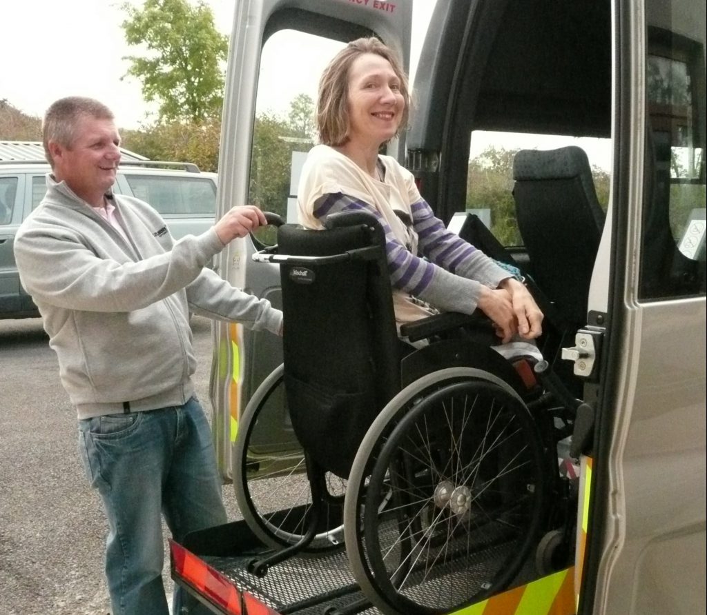 Personal Assistant assisting disabled person into accessible transport